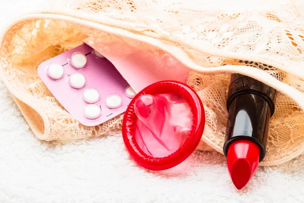 Pillole preservativo e rossetto su lingerie di pizzo — Foto Stock