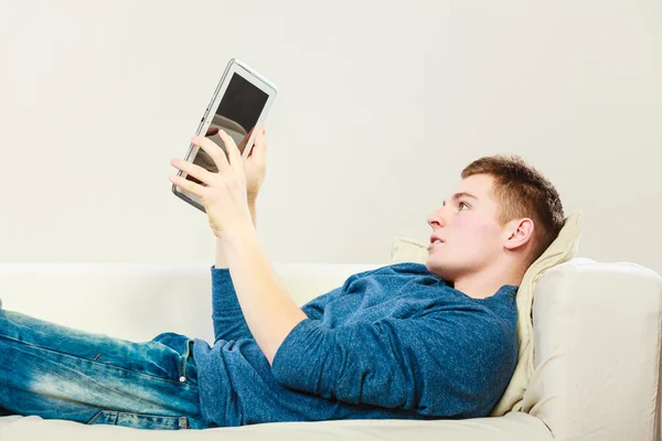 Joven con tableta digital acostado en el sofá —  Fotos de Stock