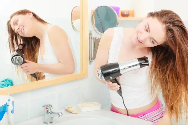 Длинноволосая женщина сушит волосы в ванной комнате — стоковое фото