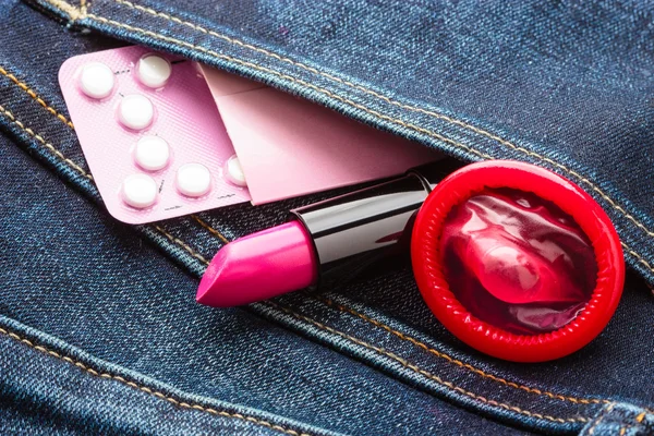 Pills condom and lipstick in denim pocket. — Stock Photo, Image