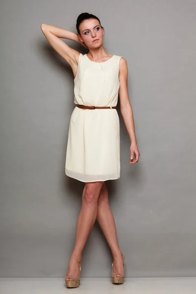 Glamour flicka i vit klänning på grå — Stockfoto