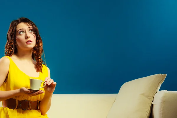 坐在沙发上的女人拿着咖啡杯 — 图库照片