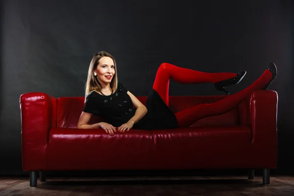 Kobieta moda w czerwone rajstopy na kanapie — Zdjęcie stockowe
