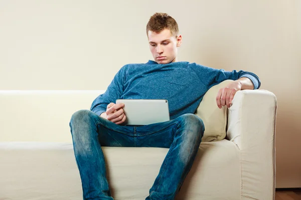 Giovane con tablet digitale seduto sul divano — Foto Stock
