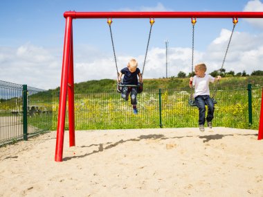 Children boys playing on swing outdoor. clipart