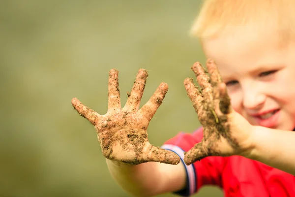 Child playing outdoor showing dirty muddy hands. — Stock Photo, Image