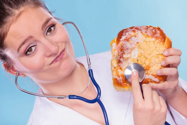 Dietitian examine sweet roll bun with stethoscope. — Stock Photo, Image