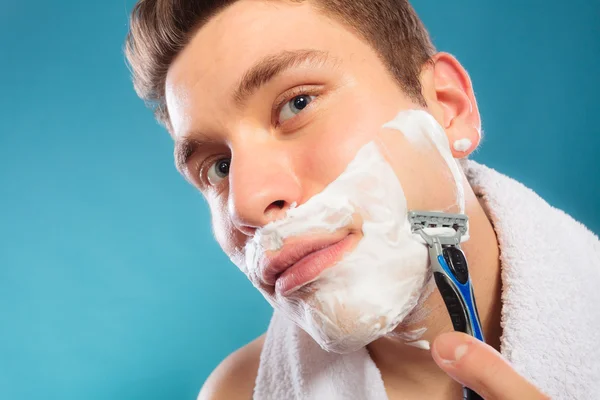 Jonge man scheren scheermes gebruiken met crème schuim. — Stockfoto