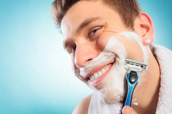 Glücklicher Mann rasiert sich mit Rasiermesser mit Sahneschaum. — Stockfoto