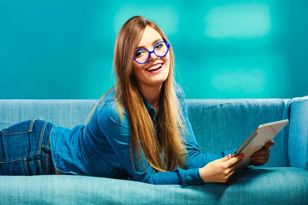 Женщина с планшетным отдыхом на диване голубого цвета — стоковое фото