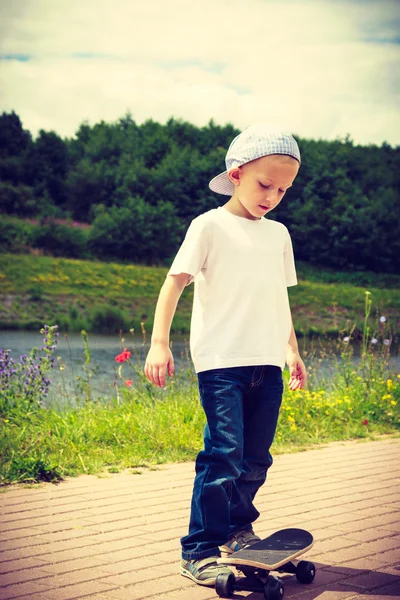 Niño deportivo con su monopatín al aire libre . — Foto de Stock