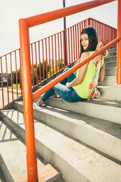 Mädchen mit Skateboard sitzend — Stockfoto