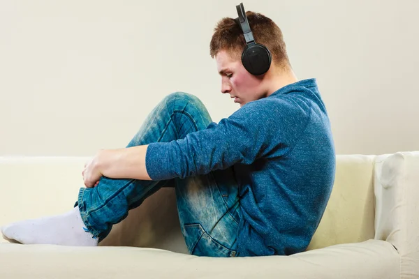 Homem com fones de ouvido sentado no sofá — Fotografia de Stock