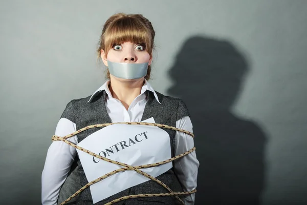 Businesswoman bound by contract with taped mouth.