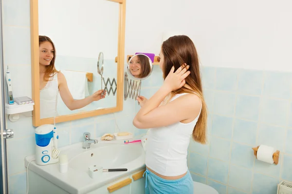 Woman without makeup in bathroom.