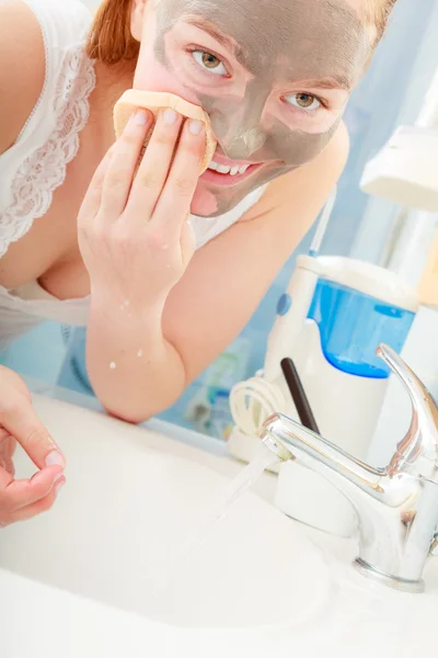 Mulher removendo máscara de barro facial lama no banheiro — Fotografia de Stock