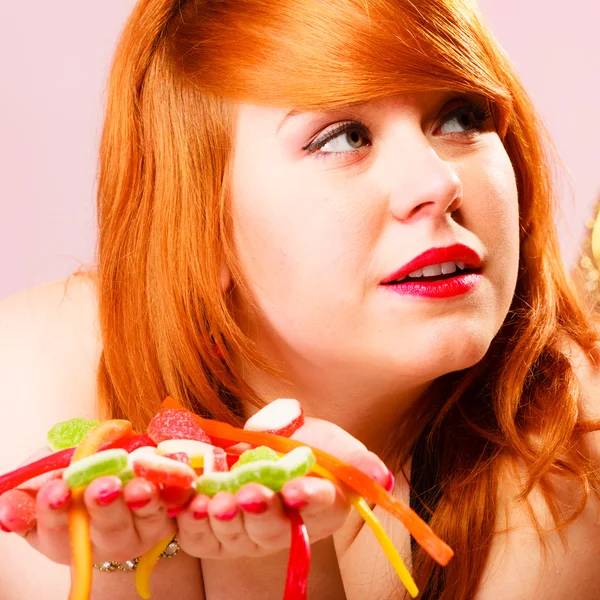 Red haired woman holding candies in hands. — Stock Photo, Image