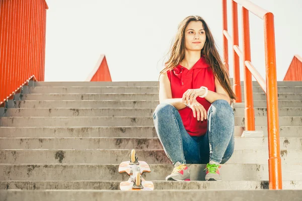 Ragazza con skateboard seduta — Foto Stock