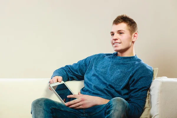 Dijital tablet kanepede oturan genç adam — Stok fotoğraf