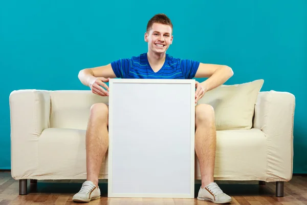 Muž drží prázdná prezentace desky na pohovce — Stock fotografie