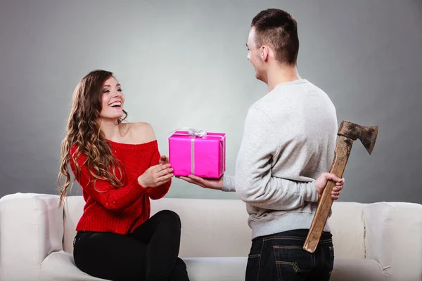 Insincire hombre sosteniendo hacha dando caja de regalo a la mujer — Foto de Stock