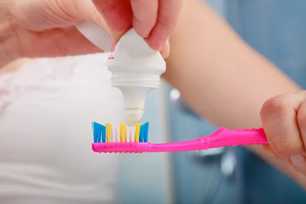 Woman hands putting toothpaste on toothbrush — Stock Photo, Image