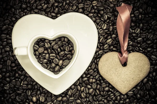 Tazza a forma di cuore e biscotti su sfondo chicchi di caffè — Foto Stock