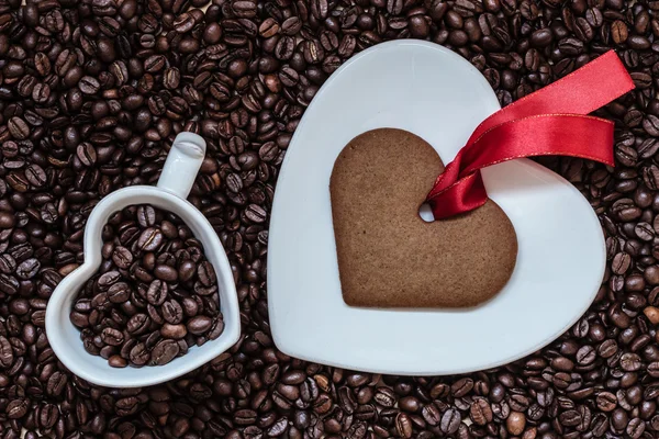 Heart shaped cup and cookie on coffee beans background