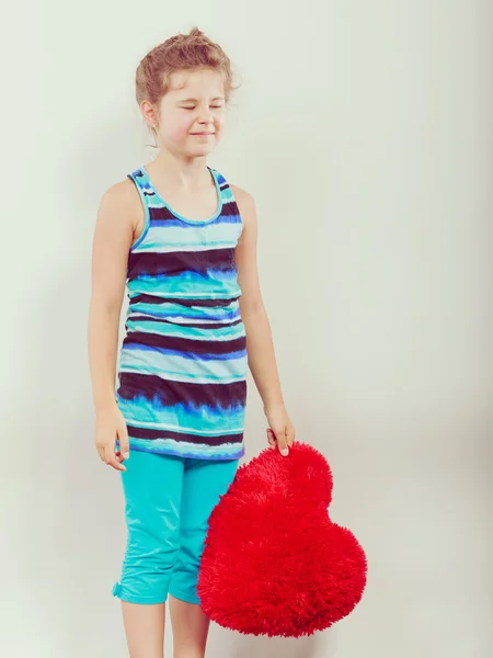 Little girl kid with red heart shape pillow. — Stock Photo, Image