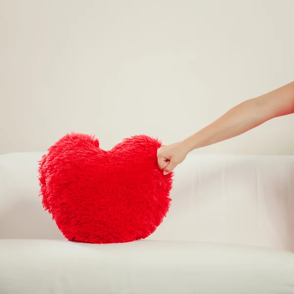 Hand punching  red heart pillow. — Stockfoto