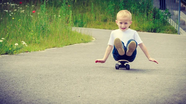 Niño sentado en el monopatín divertirse al aire libre — Foto de Stock