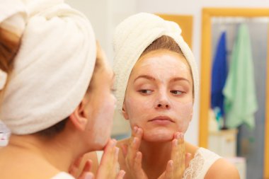 Woman applying  cream on face clipart
