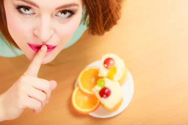 Woman eating cake showing quiet sign. Gluttony. — Stock Photo, Image