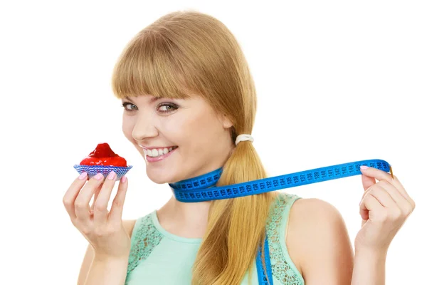 Kobieta trzyma ciastko i pomiaru taśmą. Dieta — Zdjęcie stockowe
