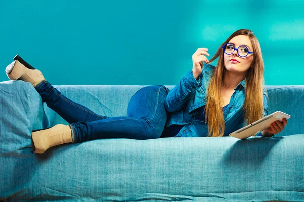 Kobieta z tabletki relaksujące na kanapie niebieski kolor — Zdjęcie stockowe
