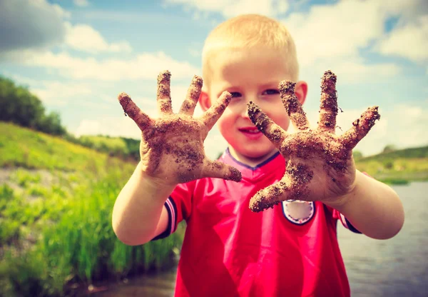 Bambino giocare all'aperto mostrando sporche mani fangose . — Foto Stock