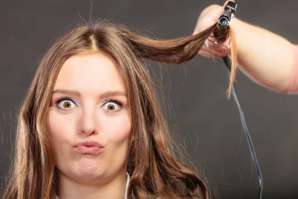 Estilista rizando el pelo para mujer joven. — Foto de Stock