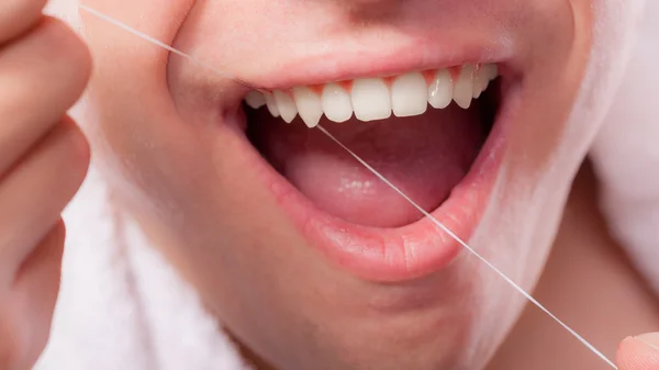 Young man cleaning her white teeth with dental floss — Stock Photo, Image