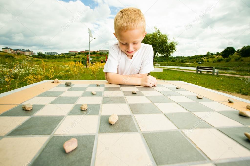 Um menino pré-escolar joga um jogo de tabuleiro de damas