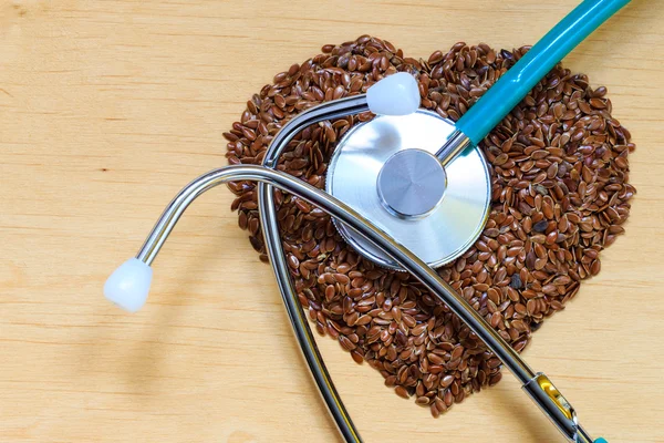 Raw flax seeds heart shaped and stethoscope — Stock Photo, Image