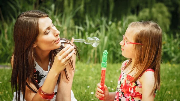 Madre y niña soplando burbujas de jabón en el parque . —  Fotos de Stock