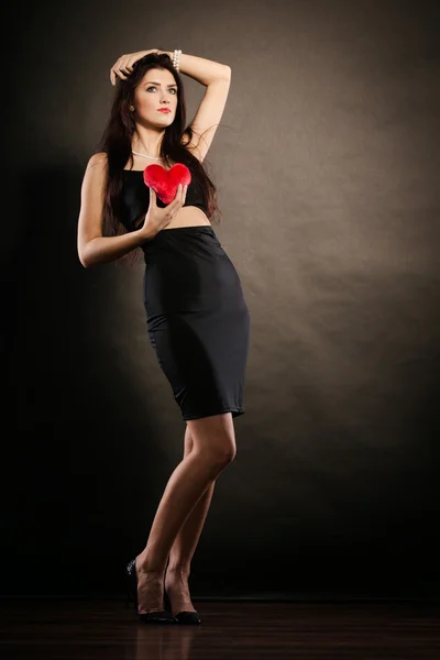 Hermosa mujer sostiene el corazón rojo en negro — Foto de Stock