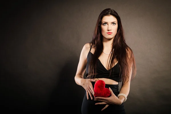 Beautiful woman holds red heart on black — Stock Photo, Image