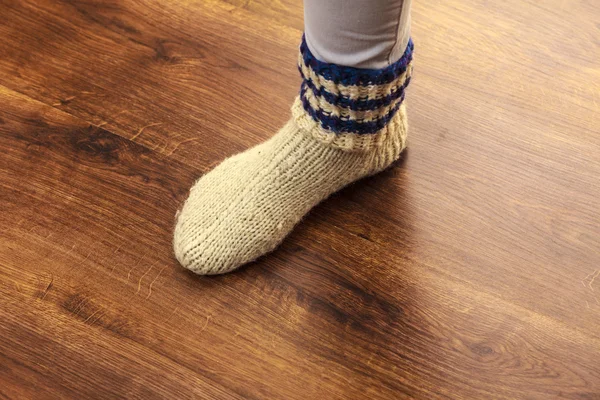 Woman foot wearing woolen warm sock on floor — Stock Photo, Image