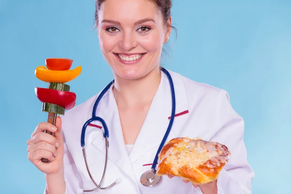 Vrouw vergelijken van ongewenste en gezonde voeding. — Stockfoto