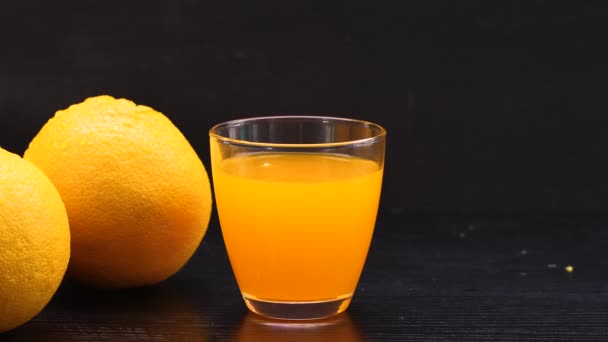 黒テーブルの上のオレンジジュースとオレンジフルーツ — ストック動画
