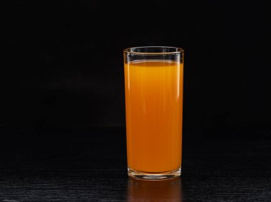 Masadaki siyah arka planlı bir bardak portakal suyu. Taze sağlıklı yiyecekler..