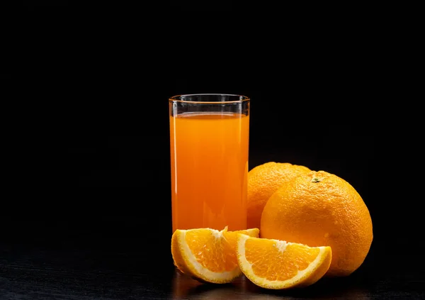 桌上放上清澈玻璃杯中的橙汁 新鲜的橙子在黑色的背景上结出水果 新鲜健康食品 — 图库照片
