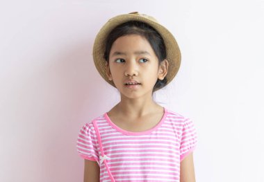 Pembe beyaz çizgili elbise giyen Asyalı bir çocuğun portresi. Kız bir şapka takmış ve ona bakıyordu..