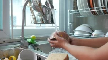 Mutfakta bulaşık yıkayan küçük bir kızın elleri.